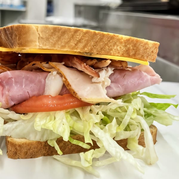 A Picnicky's Sandwich Shop sandwich with ham, turkey, bacon, cheese, lettuce, and tomato.