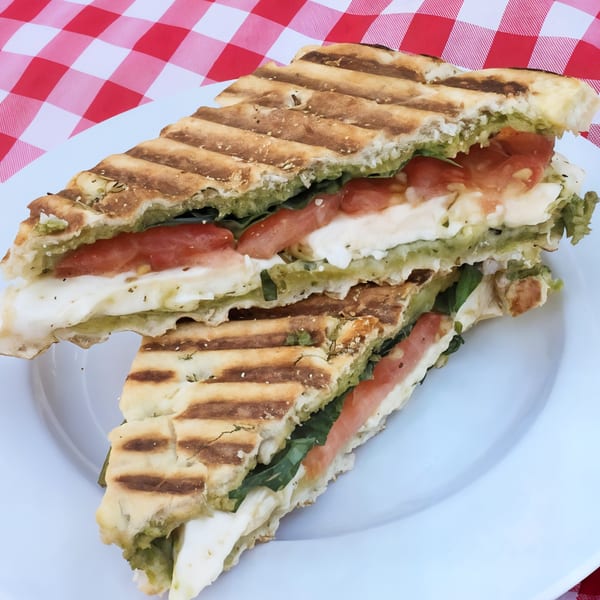 Picnicky's Caprese panini with pesto, mozzarella, tomato, and basil on a white plate.