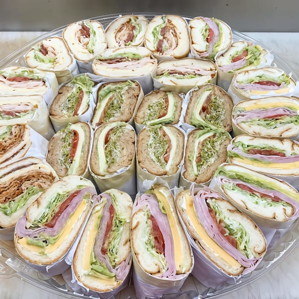 A large platter of Picnicky's Sandwich Shop sandwiches, cut in half and wrapped, showcasing various fillings.